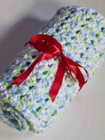 Thick and Soft Crochet Seed Stitch Baby Blanket Rolled up an tied with a red ribbon