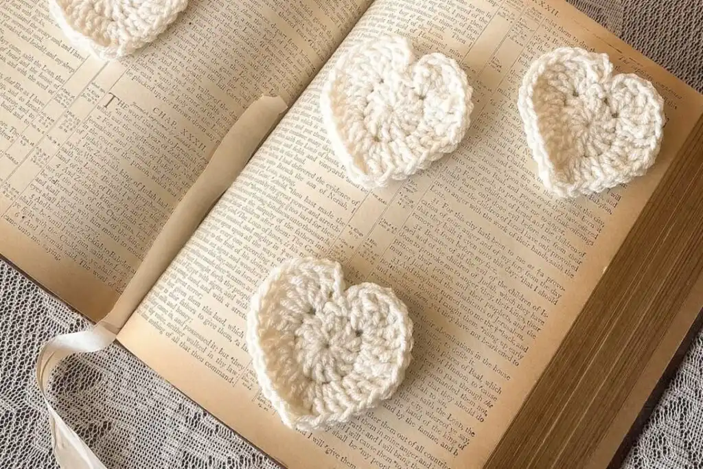 Cream crochet hearts on vintage book, lace backdrop-feature image.