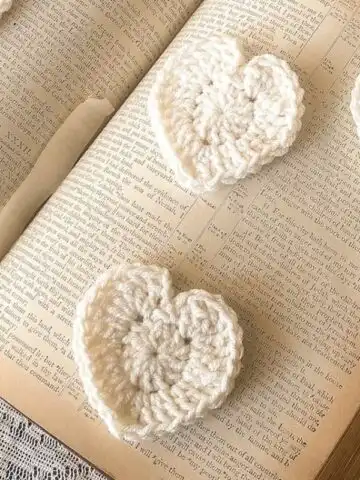 Cream crochet hearts on vintage book, lace backdrop-feature image.
