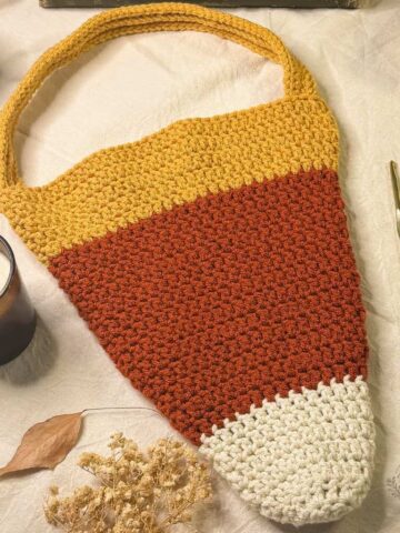 Finished bag made from the free crochet candy corn bag pattern, featuring an off-white tip, clay center, mustard top, and reinforced crochet strap.