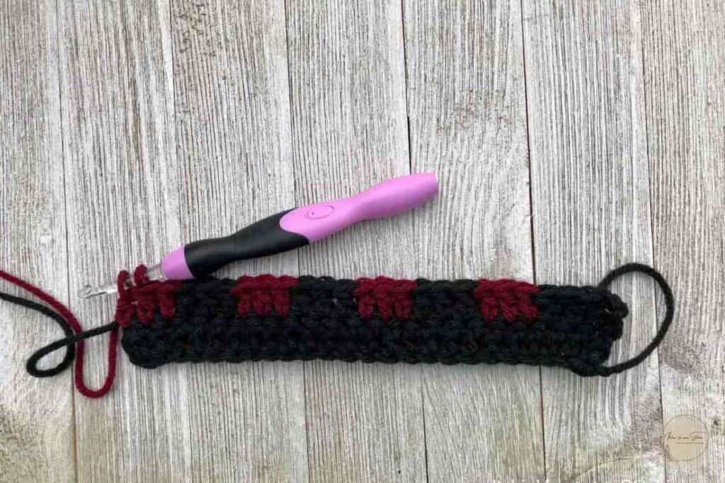Buffalo Plaid Ear Warmer crochet pattern work in progress showing the first plaid stitch row with black and burgundy yarn color changes