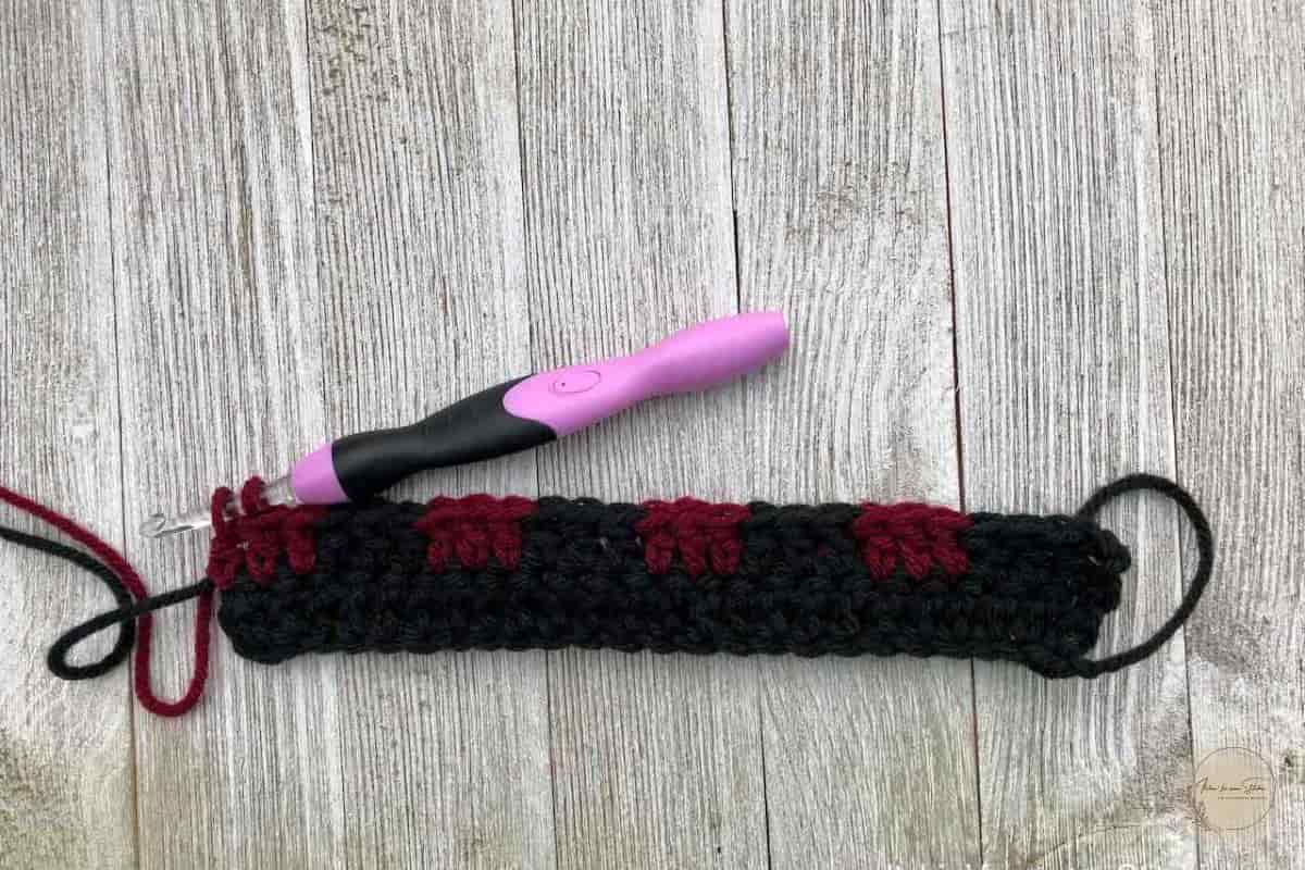 Buffalo Plaid Ear Warmer crochet pattern work in progress showing the first plaid stitch row with black and burgundy yarn color changes