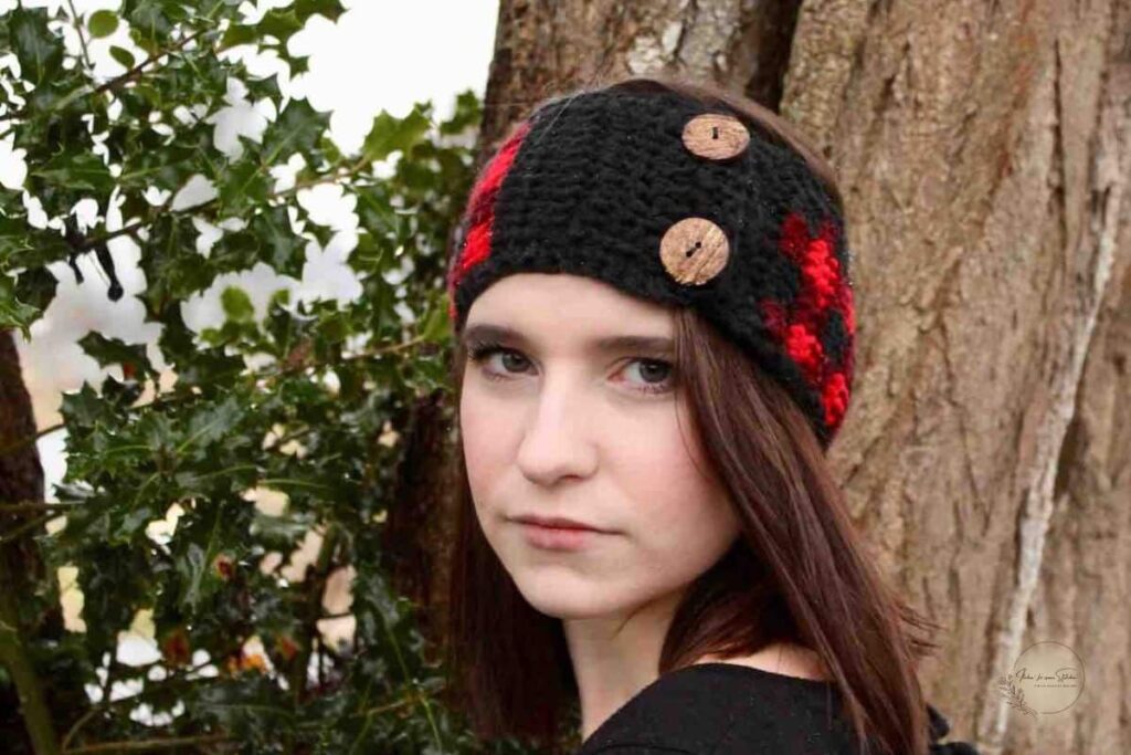 Buffalo Plaid Ear Warmer Crochet Pattern worn by a woman outdoors featuring classic red and black plaid crochet and decorative wooden buttons.