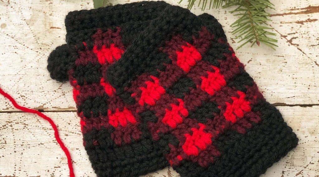 Buffalo Plaid Fingerless Gloves Crochet Pattern featuring red, burgundy, and black plaid stitch fingerless gloves displayed on a rustic wooden background.