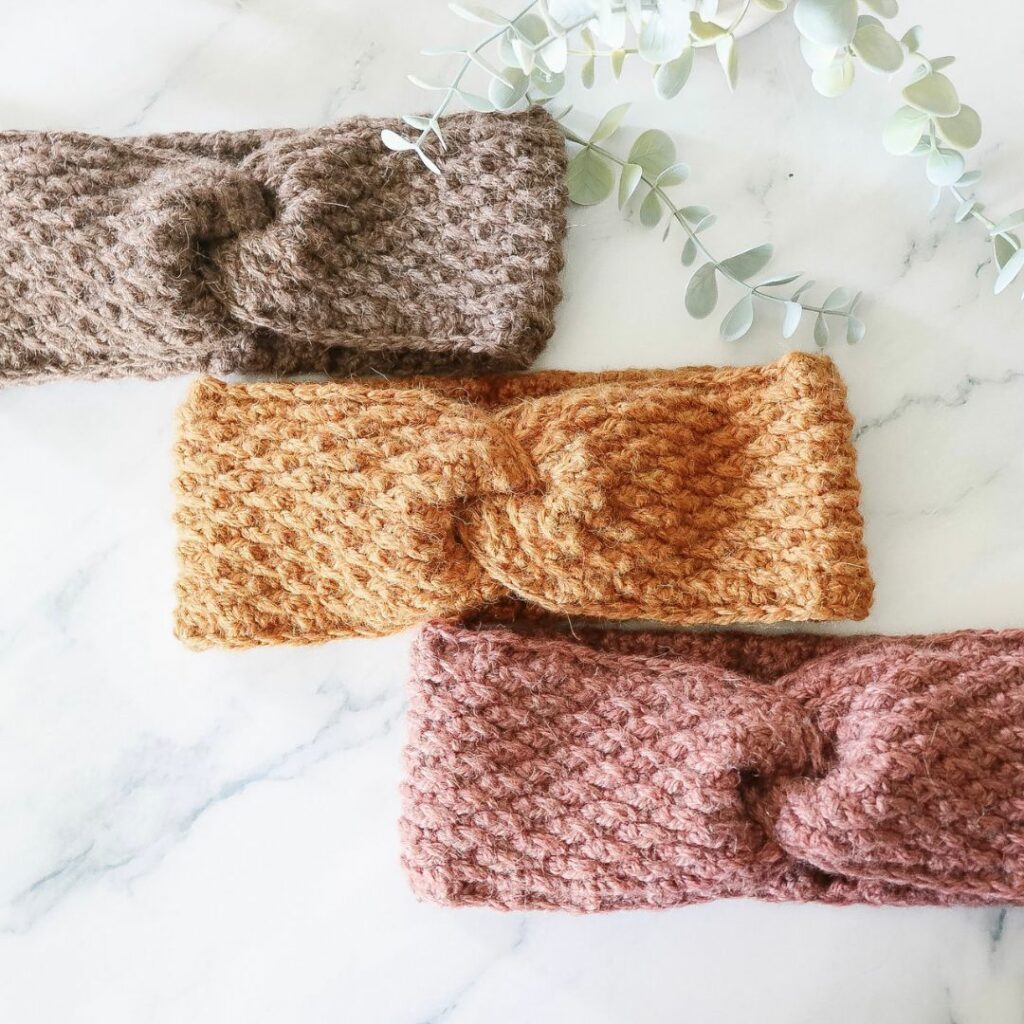 Three textured crochet twist headbands in walnut brown, mustard yellow, and blush pink.