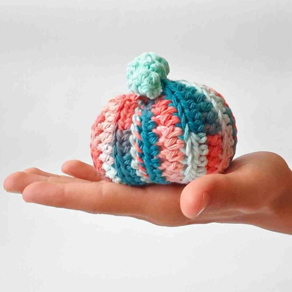 Colorful crochet pumpkin with green curly leaves.