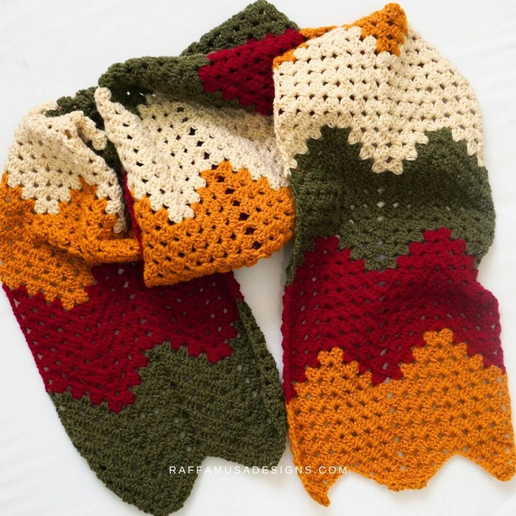 Colorful crochet granny ripple scarf featuring bold zigzag stripes in warm autumn colors.
