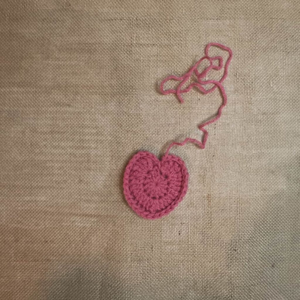 Pink crochet heart applique on a burlap background