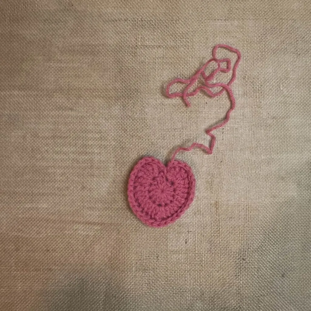 Pink crochet heart applique on a burlap background