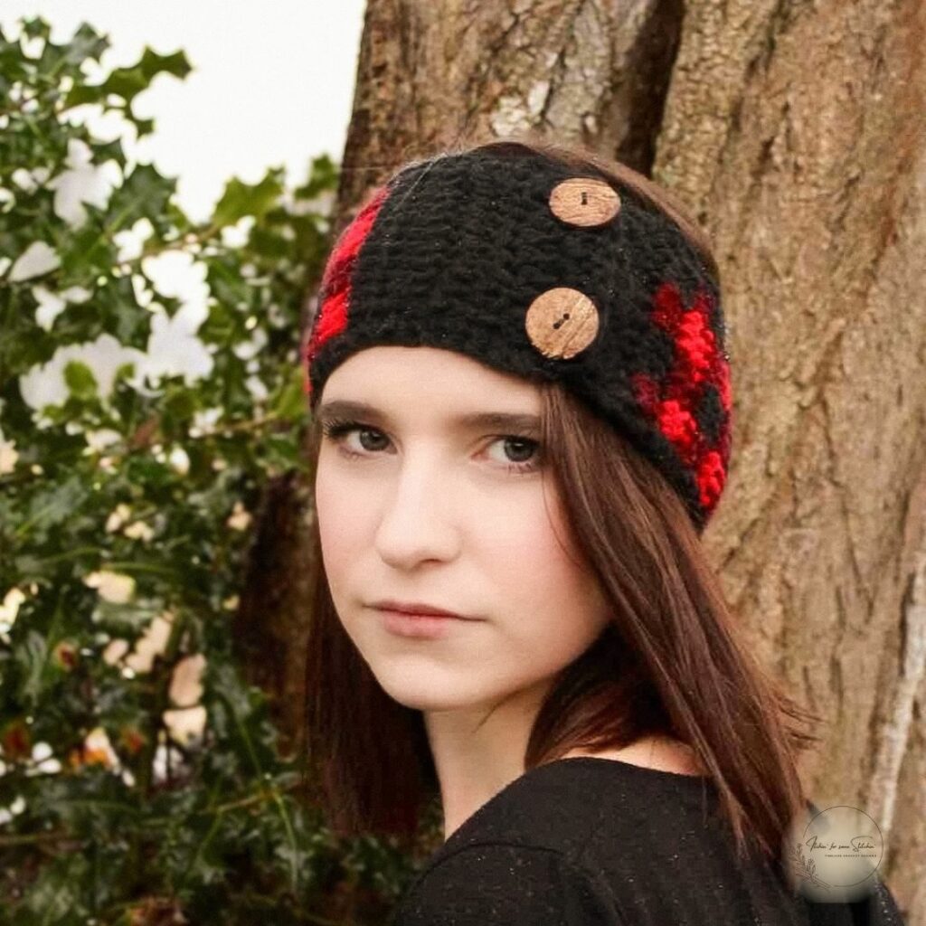 Woman wearing a red and black buffalo plaid crochet ear warmer with decorative buttons.