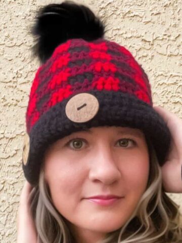 Plaid crochet beanie pattern featuring a finished buffalo plaid beanie with a folded black brim and decorative wooden buttons.