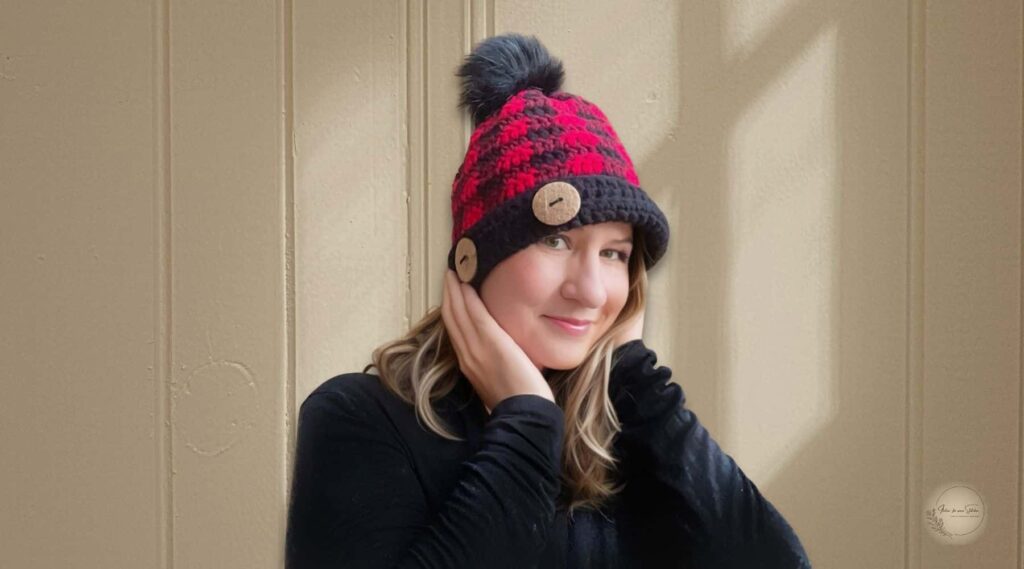 Woman modeling the Simply Chic Buffalo Plaid Crochet Beanie with decorative wooden buttons and a faux fur pom pom.