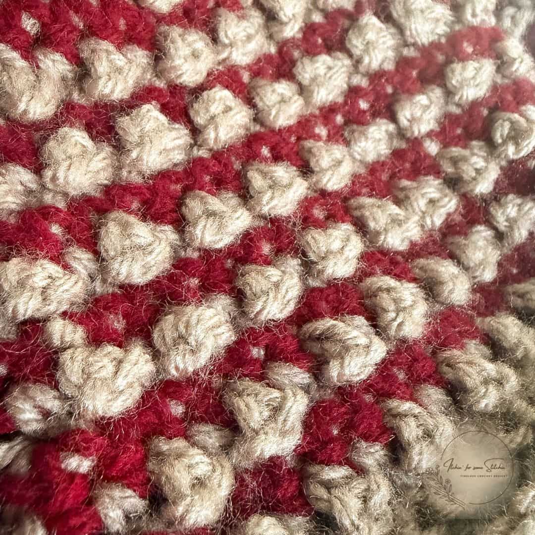 Close-up of the Everley Beanie showing raised oatmeal Mini Berry crochet stitches against contrasting burgundy stripes.