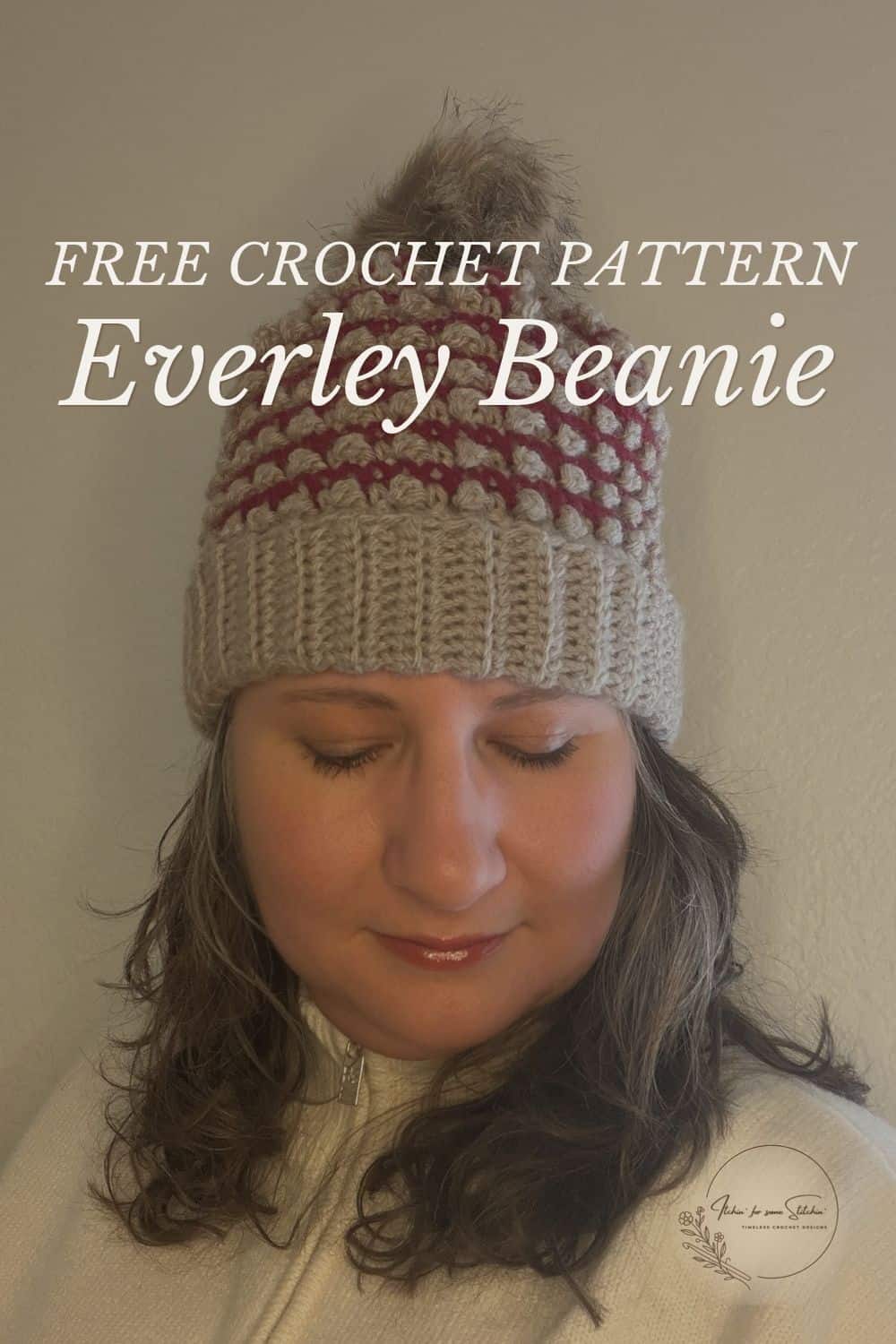 Woman wearing the Everley Beanie, a burgundy and oatmeal berry stitch crochet hat with a folded ribbed brim and faux fur pom-pom. Image reads “Free Crochet Pattern Everley Beanie.”